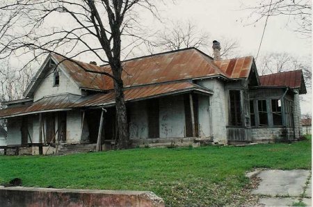 The metal roof, masonry walls, and front porch in need of repair, 1993.