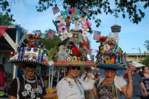 Three friends show off their sombreros piled high with decorations and San Antonio memorabilia.