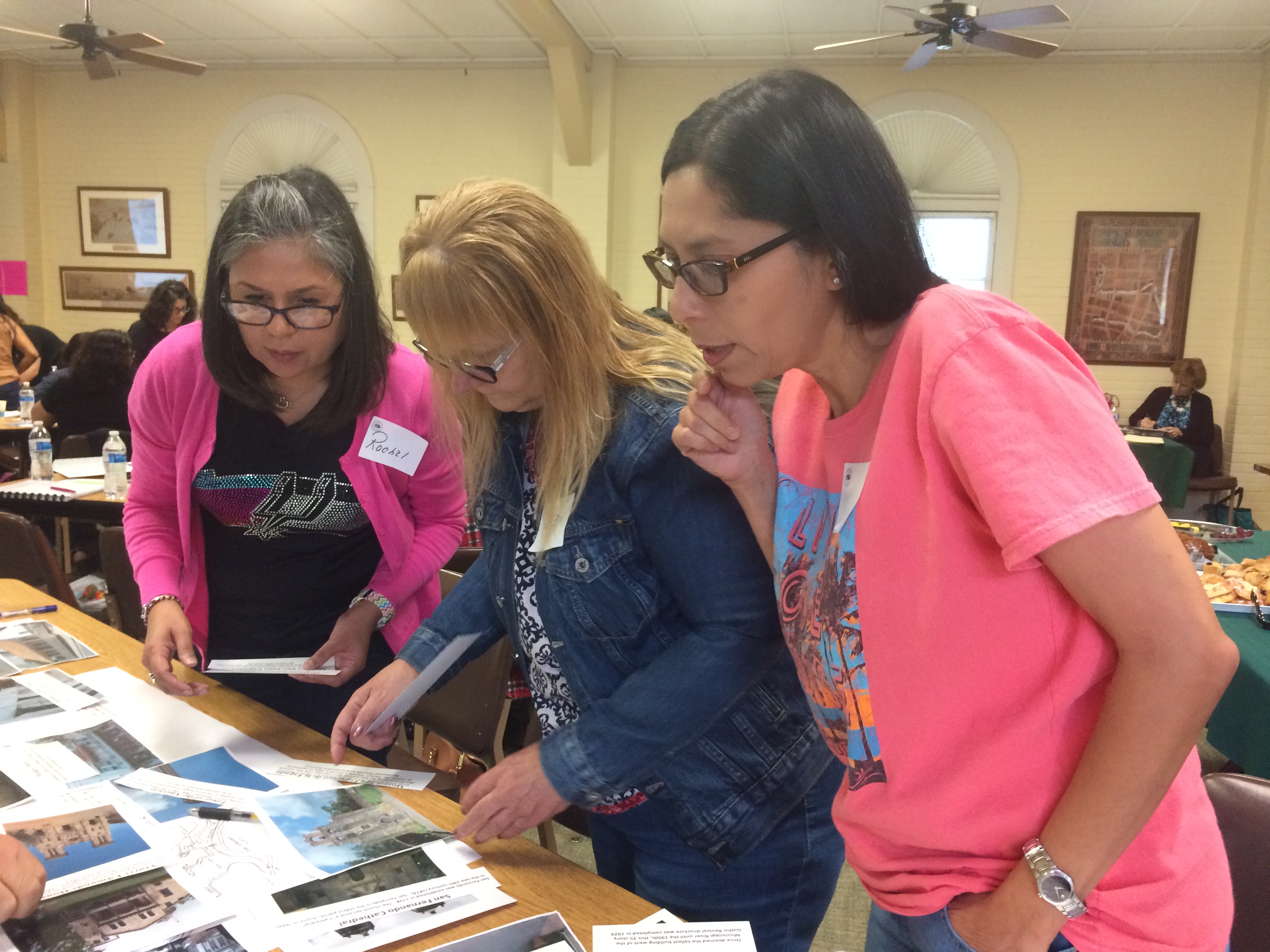 Three teachers at Teacher Education Seminar reviewing workshop materials in the River House