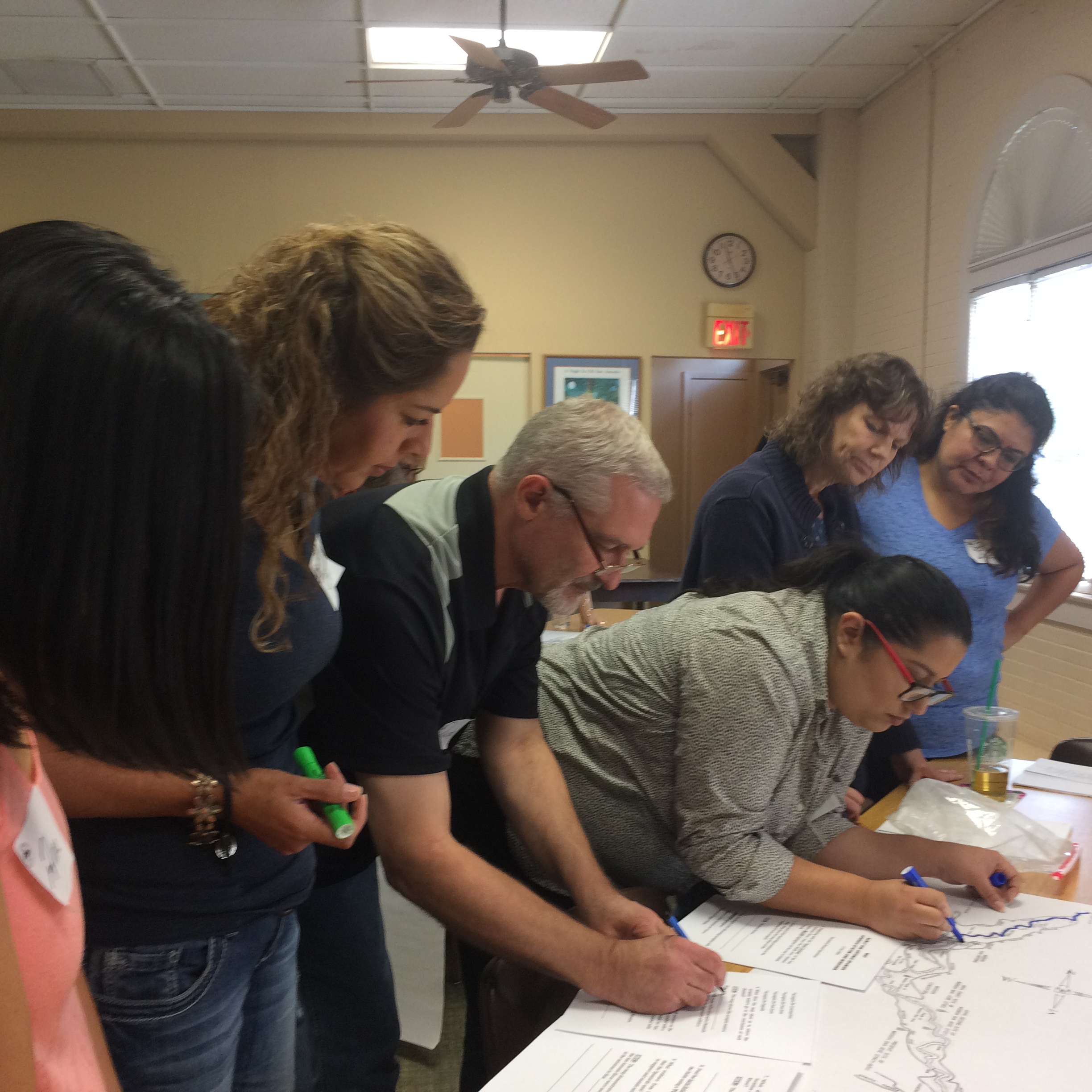 Large group of teachers marking drawings for workshop during Teacher Education Seminar in the River House