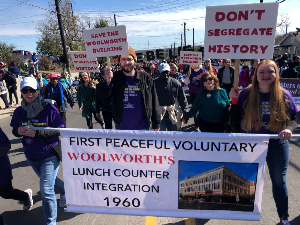 Supporters of preserving the Woolworth Building carry a banner and signs in the MLK March