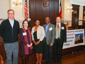 Five symposium speakers stand next to Woolworth banner.