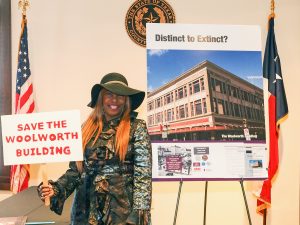 Kathleen Carter-Stiggers holds "Save the Woolworth Building" sign next to a poster of the building.