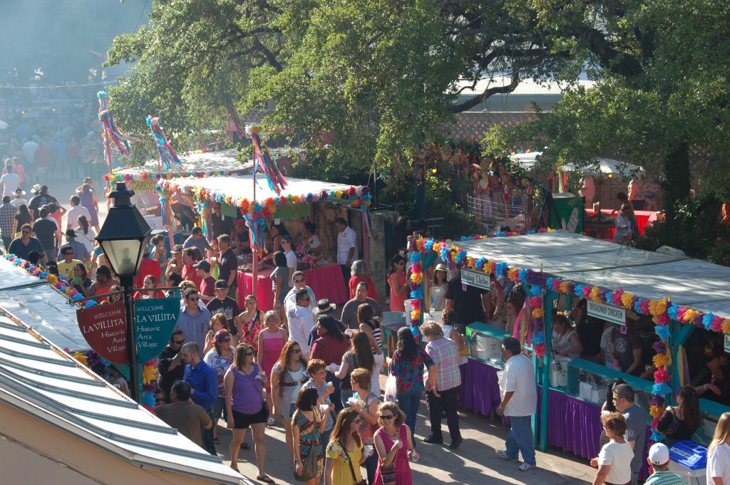 People walking by colorful NIOSA booths in La Villita