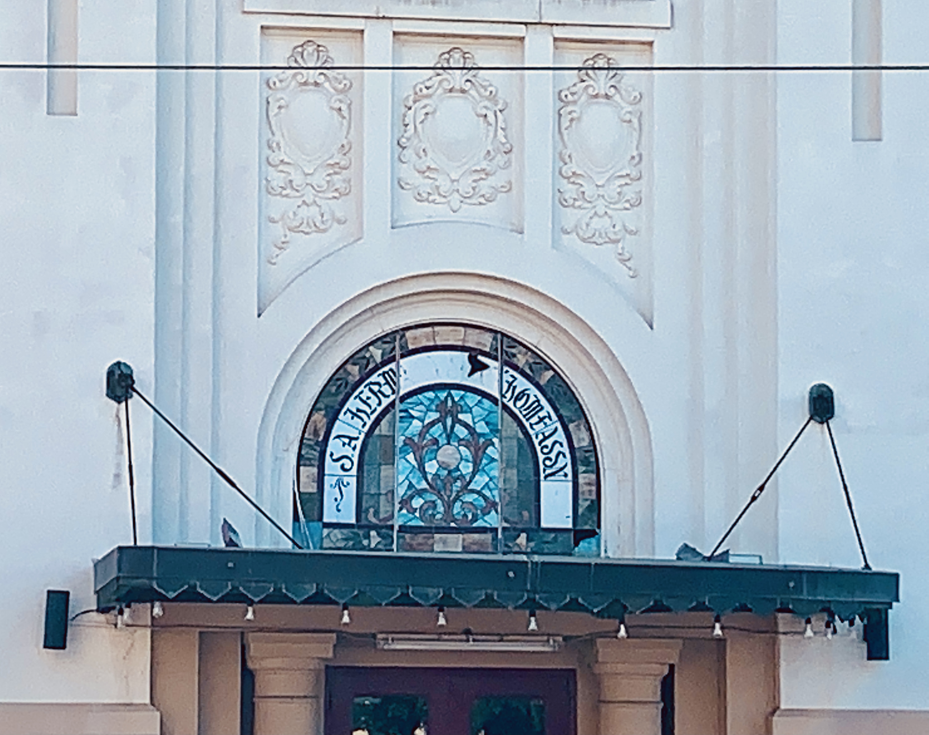 Arched stained glass window above entrance to Hermann Sons building.